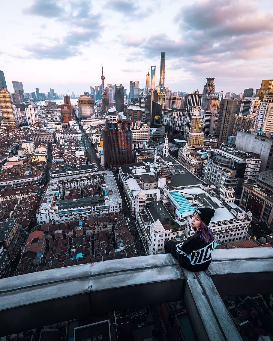 woman-sitting-on-rooftop-looking-backward-overlooking-city