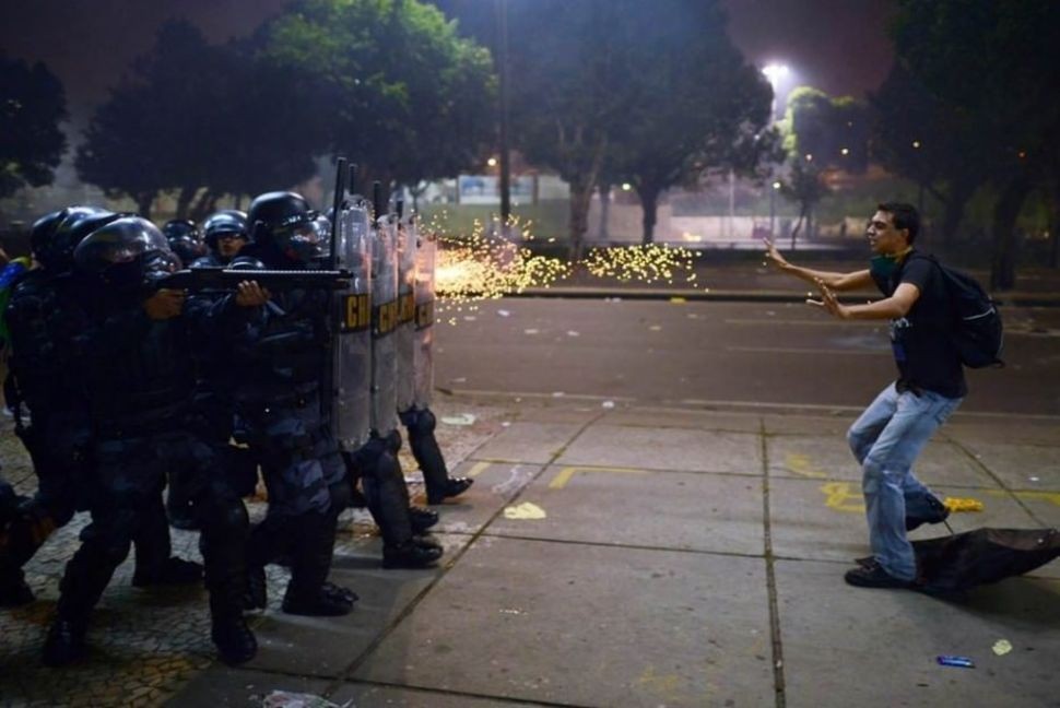 مواطن برازيلى يقف أمام اطلاق النار فى المظاهرات التى انطلقت ضد فساد ووحشية الشرطة