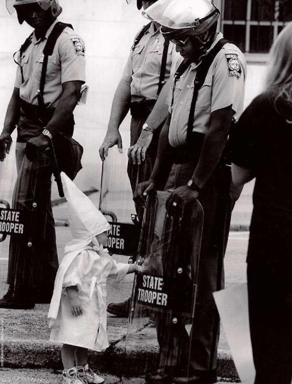 أحد الأطفال يلمس انعاكسة على درع أحد رجال شرطة مكافحة الشغب بأمريكا عام 1992