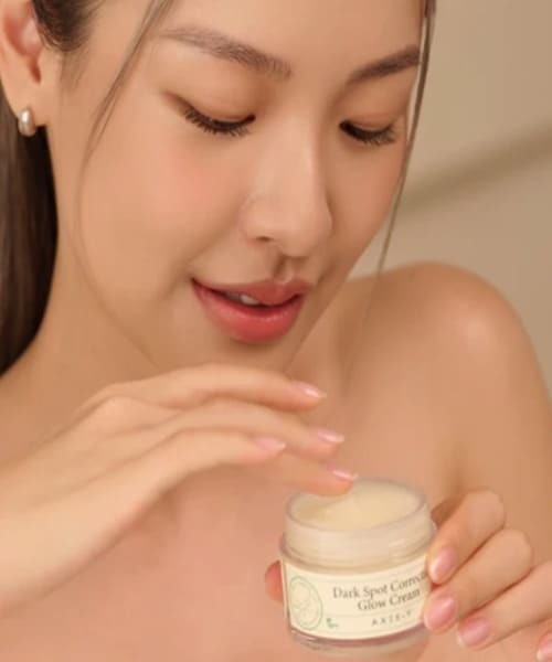 فتاة تحمل علبة AXIS-Y Dark Spot Correcting Glow Cream